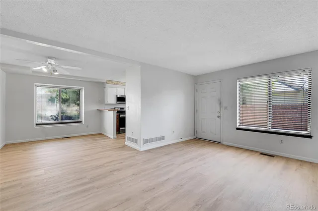 an empty room with wooden floor and windows