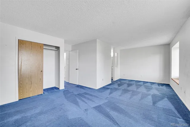 a view of an empty room with wooden floor and window