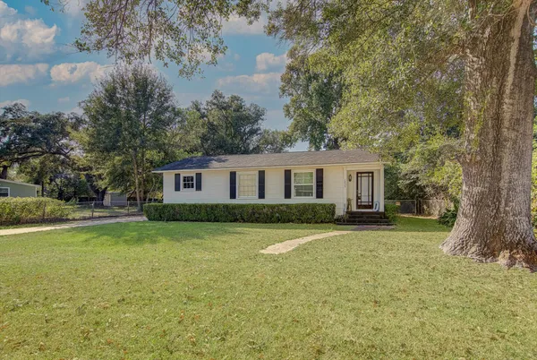 a front view of a house with a garden and trees