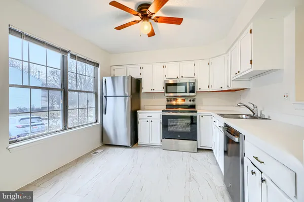 a kitchen with a refrigerator a stove top oven a sink dishwasher and white cabinets with wooden floor