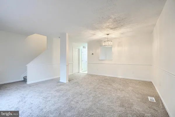 an empty room with chandelier fan and windows