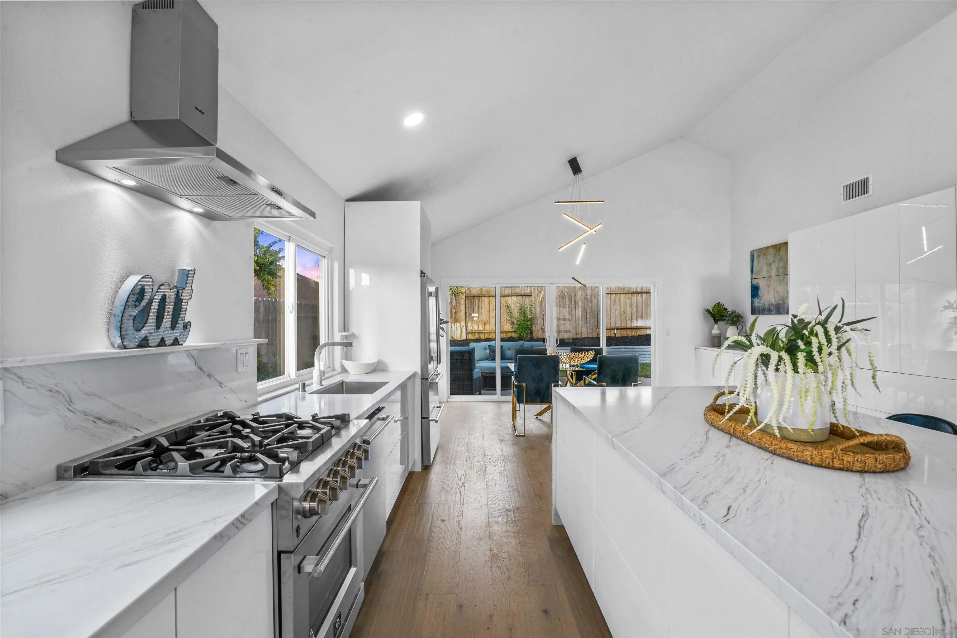 113 Solace Court Encinitas, CA 92024 - Photo 11 of 38 a kitchen with stainless steel appliances granite countertop a white stove top oven a dining table and chairs with wooden floor