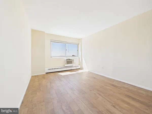 a view of an empty room with a window and wooden floor
