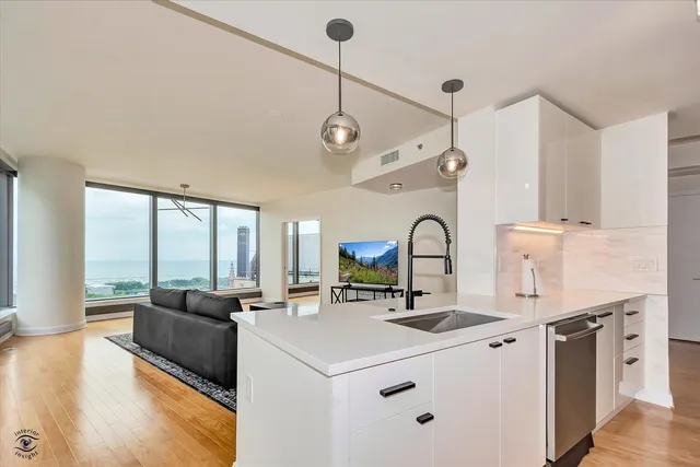a view of living room with granite countertop furniture a sink a flat screen tv and large windows