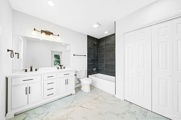 a spacious bathroom with a double vanity sink a toilet and a shower