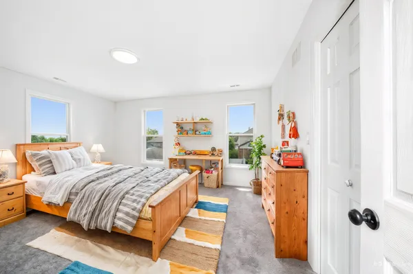 a bedroom with a bed and a dresser next to a window