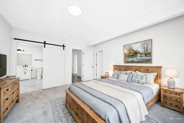 a spacious bedroom with a bed and a flat screen tv