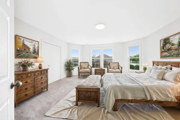 a spacious bedroom with a bed a dresser and next to a window