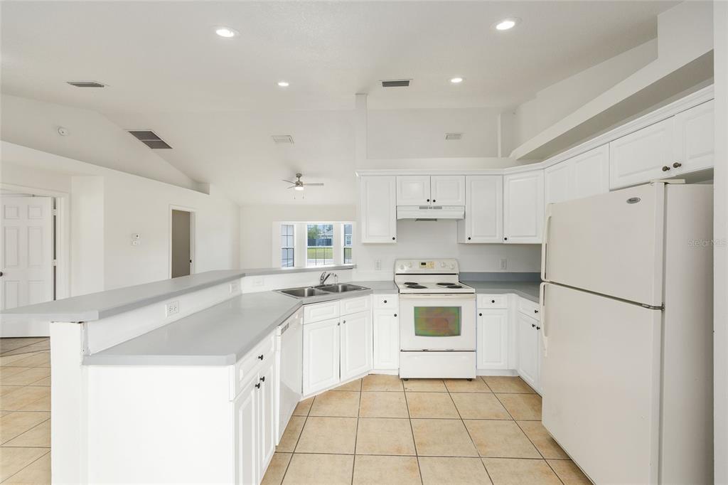 15434 Southwest 23rd Court Road Ocala, FL 34473 - Photo 20 of 41 a kitchen with a sink a stove a refrigerator and white cabinets