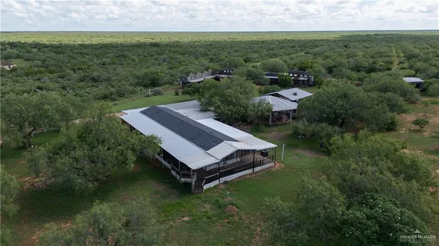an aerial view of a house with pool big yard and large trees
