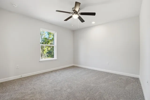 an empty room with a window and a fan