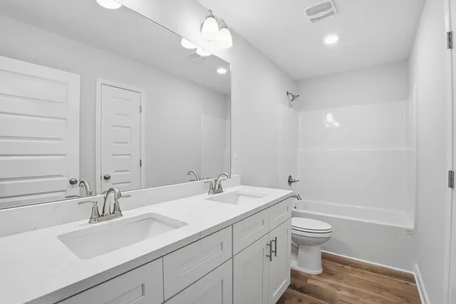 a bathroom with a double vanity sink a toilet and a large mirror