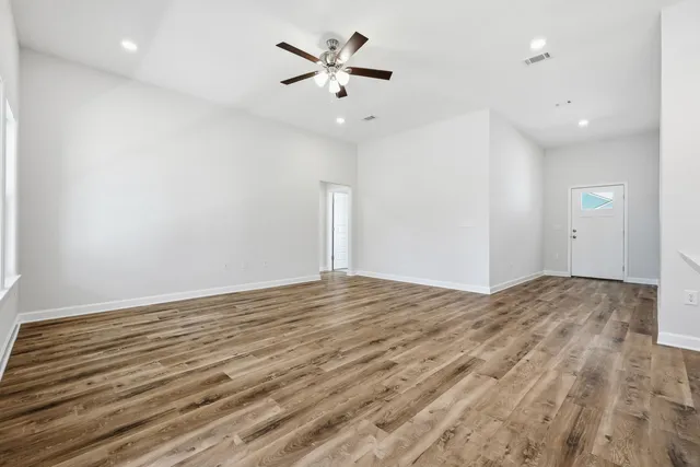 an empty room with wooden floor and ceiling fan
