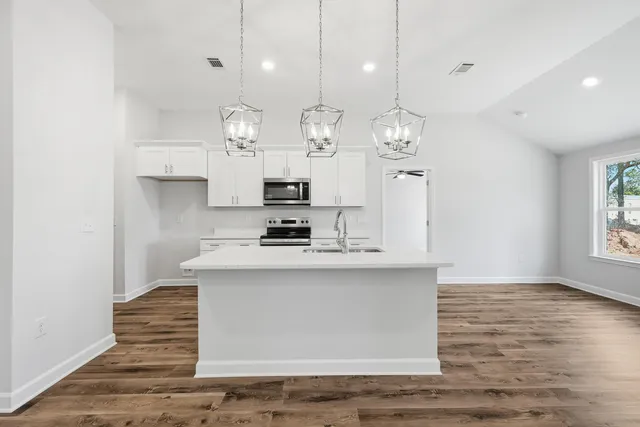 a large kitchen with chandelier and stainless steel appliances