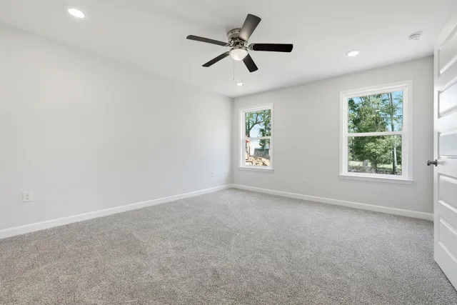 an empty room with windows and ceiling fan
