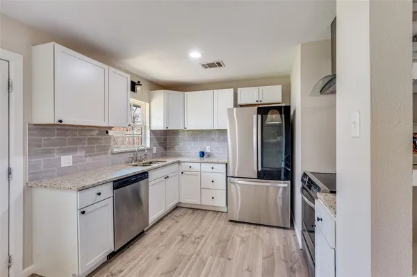 a kitchen with cabinets stainless steel appliances a sink and a window