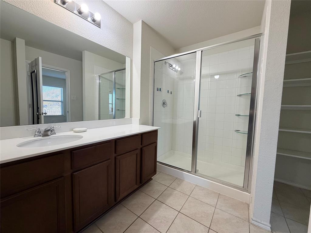 2203 Vance Drive Forney, TX 75126 - Photo 13 of 23 Bathroom featuring vanity, a stall shower, light tile patterned floors, and a textured ceiling