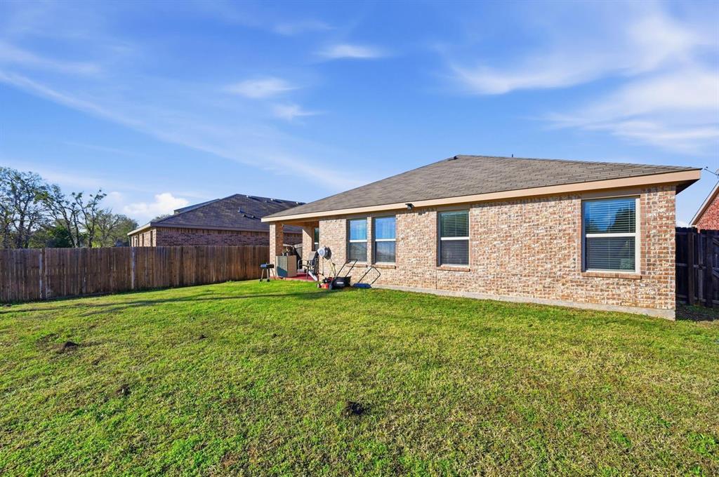 2203 Vance Drive Forney, TX 75126 - Photo 20 of 23 Back of property featuring a fenced backyard, brick siding, a patio area, and roof with shingles