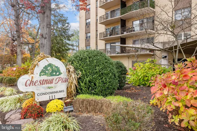 a front view of a multi story residential apartment building with yard and sign board