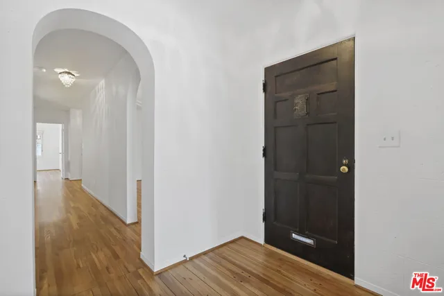 an empty room with wooden floor fireplace and windows