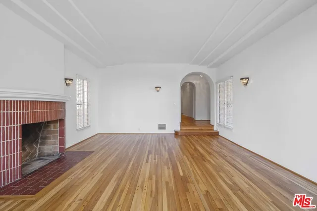 a view of empty room with wooden floor and fireplace