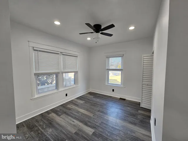 an empty room with wooden floor fan and windows