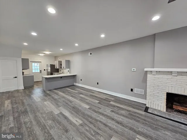 a living room with stainless steel appliances furniture a fireplace and a ceiling fan