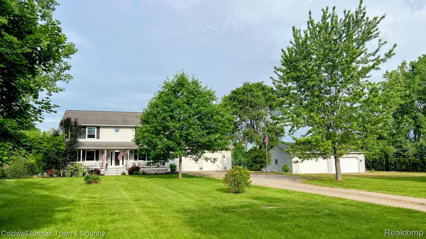 717 North Youngs Road Attica, MI 48412 - Photo 1 of 87 Two-story residence with 2.5 car garage, featuring light-colored siding, dark shutters, and a covered front porch with and 4 car detached garage/workshop