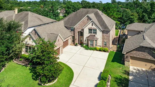 an aerial view of a house with a yard and trees all around