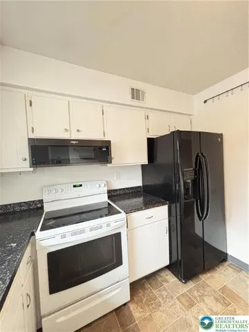 a kitchen with granite countertop white cabinets and white appliances