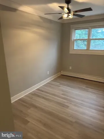 an empty room with wooden floor chandelier fan and windows