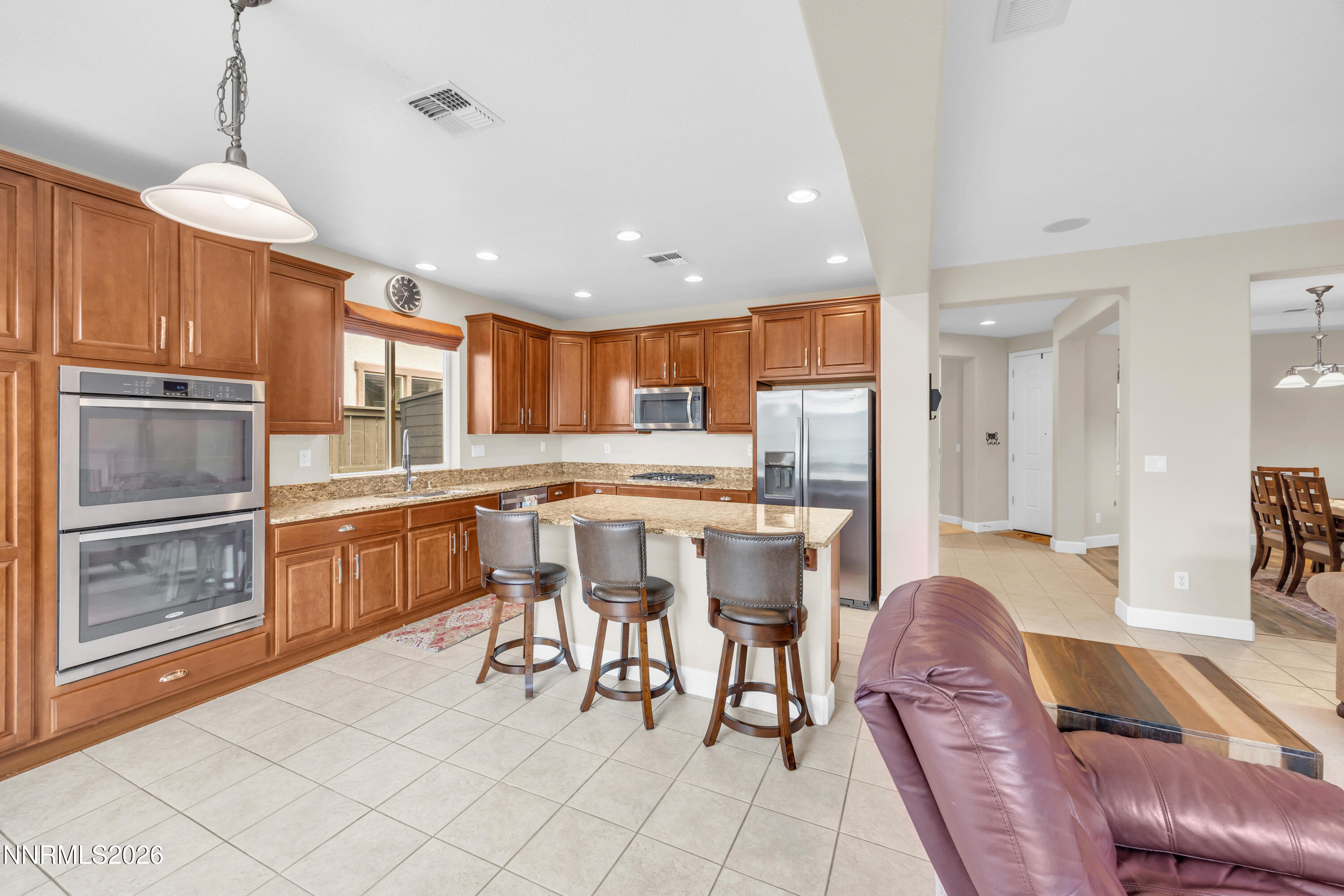 7119 Coldwater Street Sparks, NV 89436 - Photo 24 of 45 a kitchen with stainless steel appliances kitchen island granite countertop a refrigerator a stove a sink a dining table and chairs with wooden floor