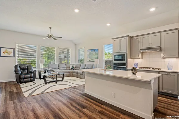 a kitchen with stainless steel appliances granite countertop a stove top oven a sink dishwasher a dining table and chairs with wooden floor