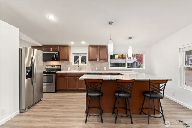 a kitchen with stainless steel appliances granite countertop a refrigerator a sink dishwasher a stove with wooden floor and cabinets