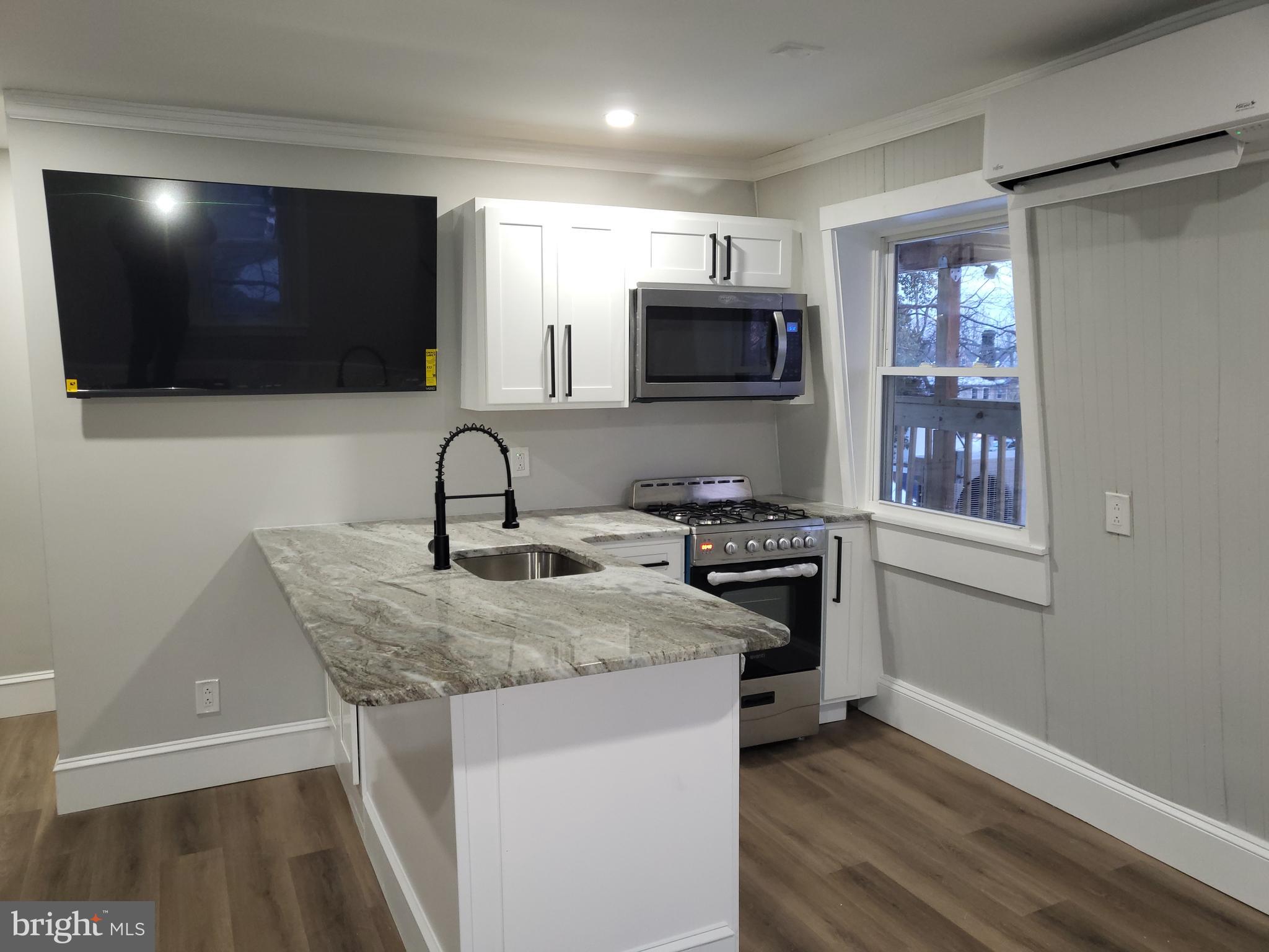 212 Warren Street Beverly, NJ 08010 - Photo 30 of 33 a kitchen with stainless steel appliances granite countertop a stove a sink and a microwave