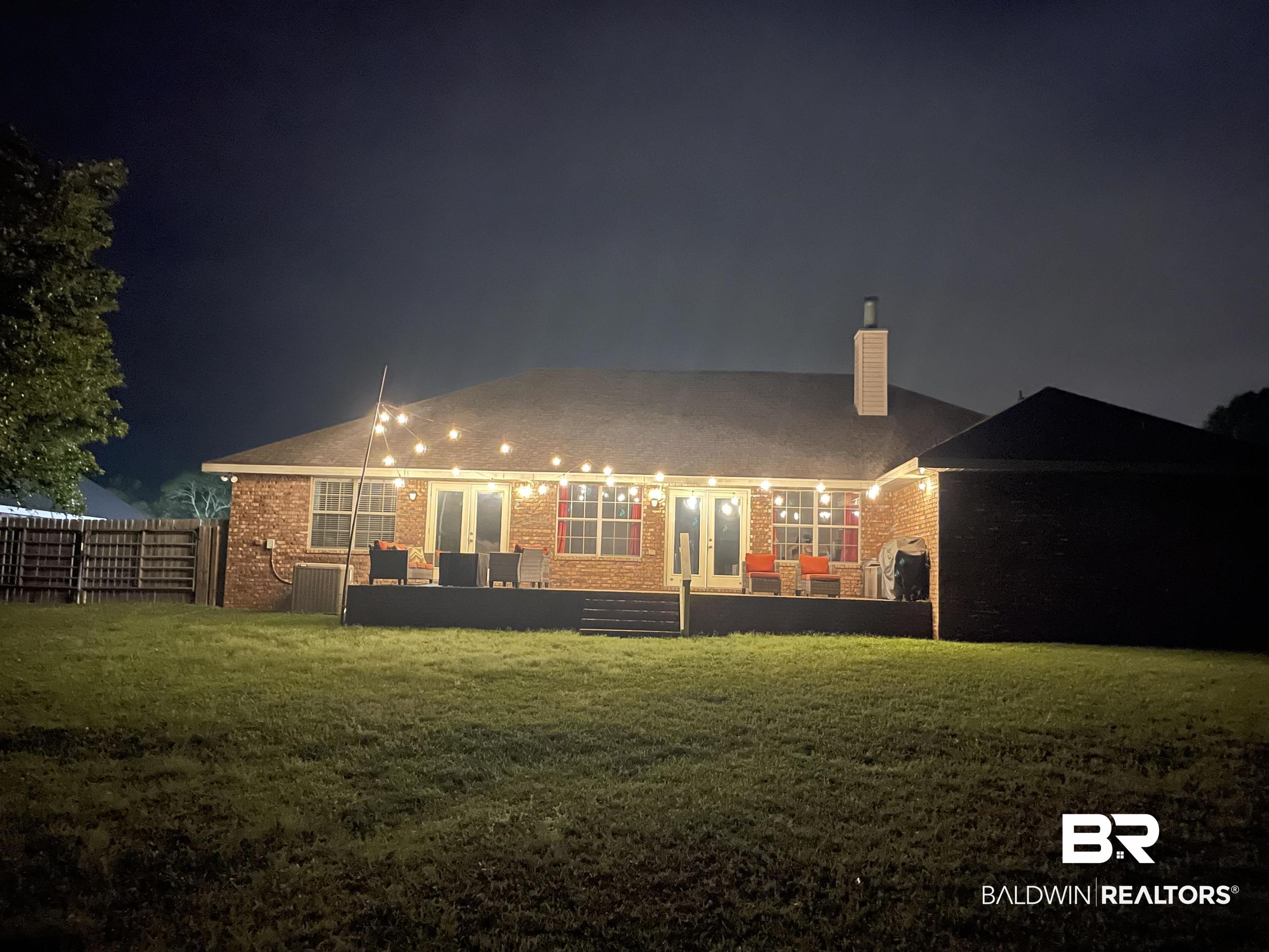 10753 Rigby Drive Mobile, AL 36695 - Photo 25 of 33 Back of house at twilight featuring a chimney, fence, french doors, brick siding, and a lawn