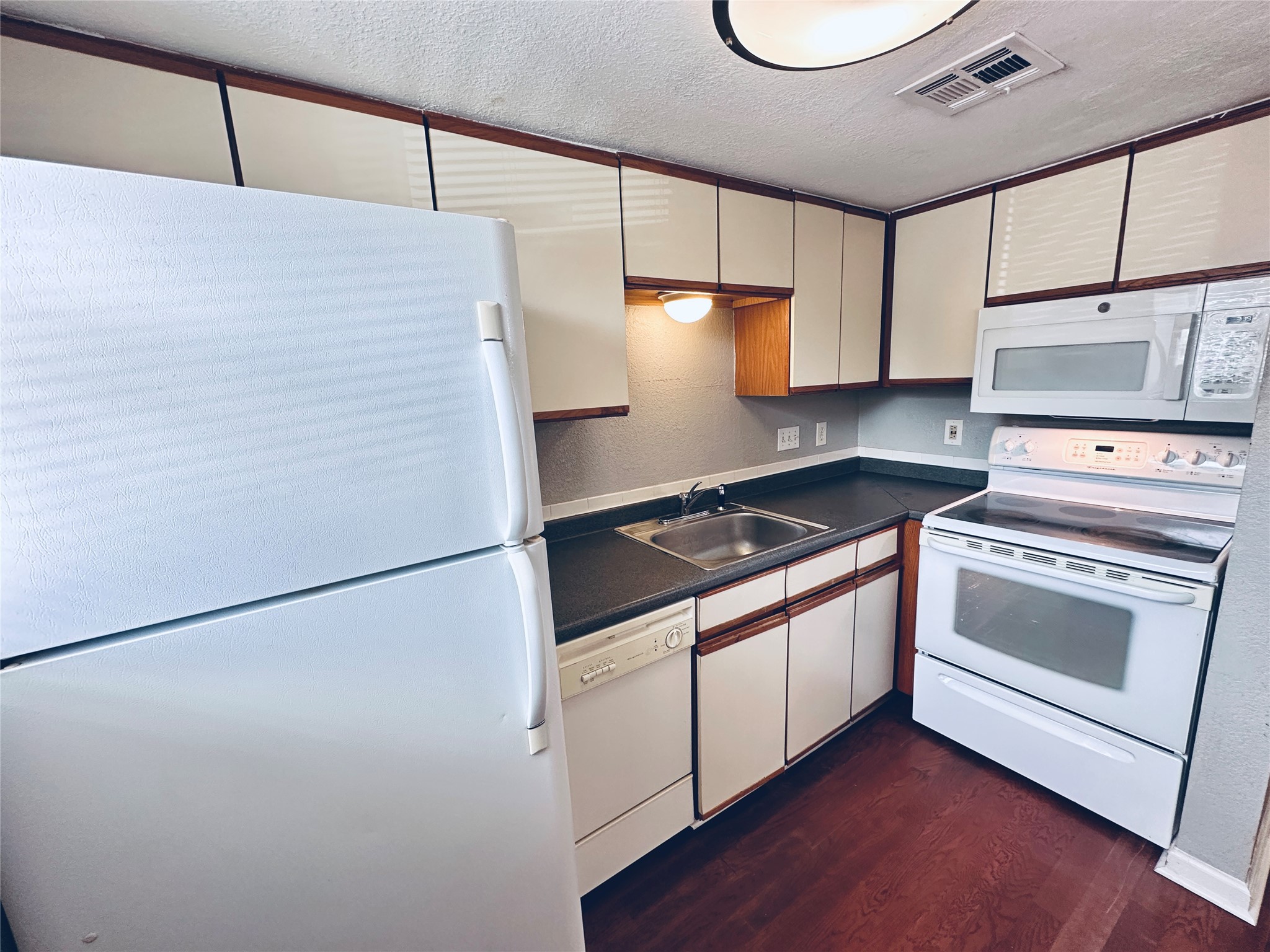2500 Burleson Road, Unit 209 Austin, TX 78741 - Photo 8 of 24 A compact culinary space featuring classic white appliances and contrasting cabinetry.