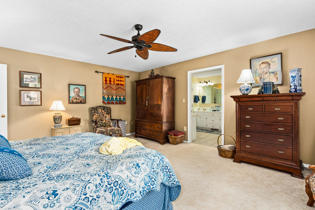 365 Calihan Road Booneville, AR 72927 - Photo 42 of 59 Carpeted bedroom with a ceiling fan, neutral wall color, and a partial view of an attached bathroom featuring a dual vanity with light-colored cabinetry