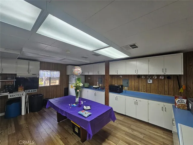 a kitchen with stainless steel appliances kitchen island granite countertop a sink dishwasher stove top oven and cabinets with wooden floor