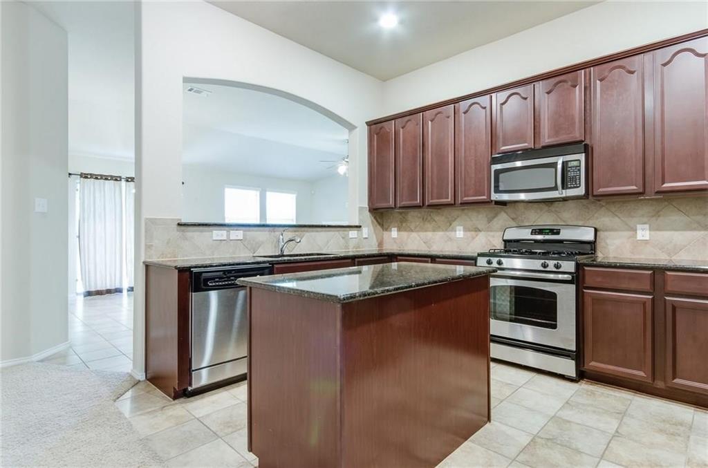 3404 Evening Wind Road Denton, TX 76208 - Photo 15 of 24 a kitchen with stainless steel appliances granite countertop wooden cabinets a stove a sink and a microwave