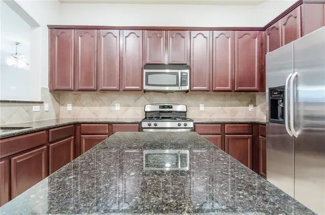 a kitchen with granite countertop a refrigerator stove and sink