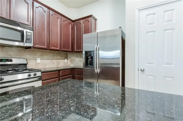 a kitchen with granite countertop a refrigerator and a stove top oven