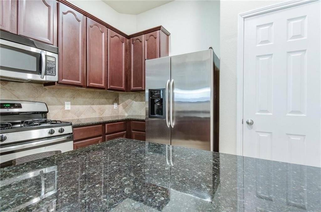 3404 Evening Wind Road Denton, TX 76208 - Photo 17 of 24 a kitchen with granite countertop a refrigerator and a stove top oven