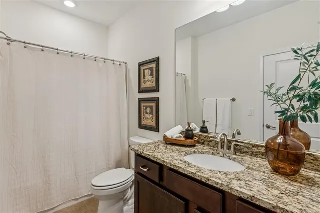 a bathroom with a granite countertop sink a toilet and a mirror
