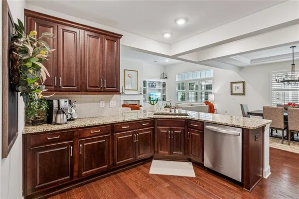 a kitchen with stainless steel appliances granite countertop wooden cabinets a sink and dishwasher with wooden floor