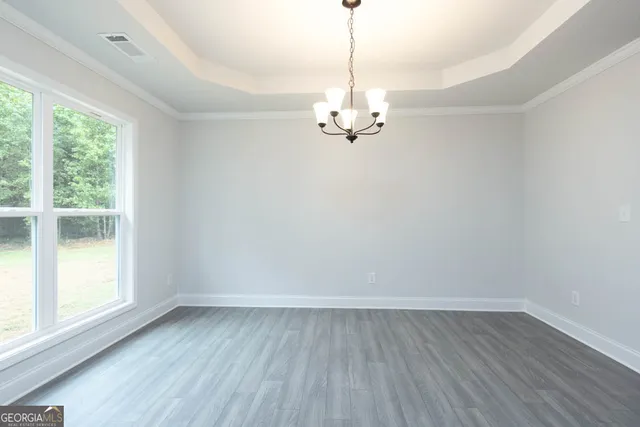 a view of empty room with wooden floor fan and window
