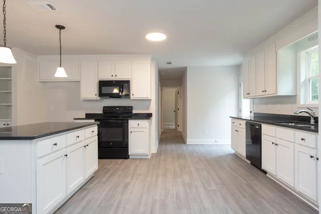 a kitchen with granite countertop a stove top oven a sink dishwasher and a refrigerator with wooden floor