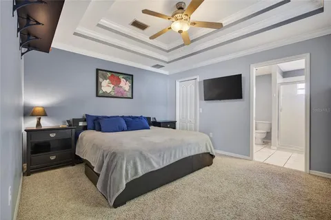 a bedroom with a bed and a flat tv screen on dresser