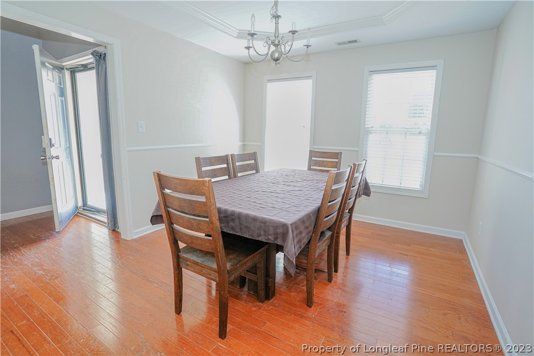10 Pender Road Spring Lake, NC 28390 - Photo 6 of 30 a dining room with wooden floor a chandelier a wooden table and chairs