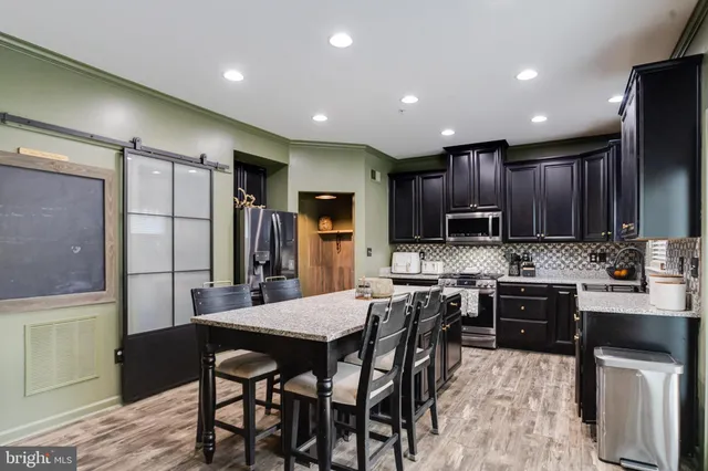 a kitchen with kitchen island wooden cabinets a refrigerator and a stove top oven